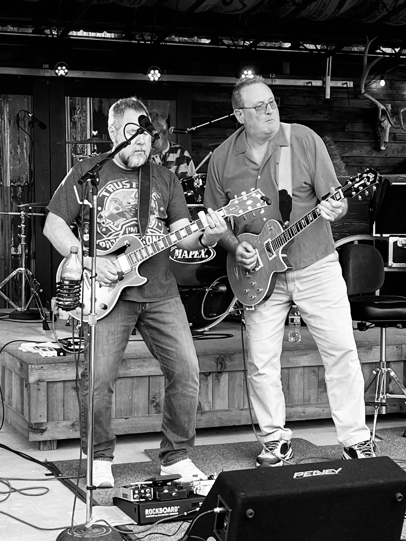 Two guitarists playing side by side on an outdoor stage