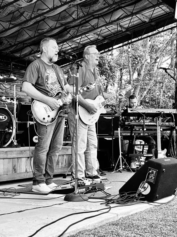 Two guitarists singing, keys player in the background